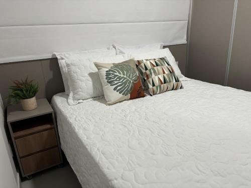 a bed with white sheets and pillows on it at Studio Live 1 Moderno e Aconchegante in Uberlândia