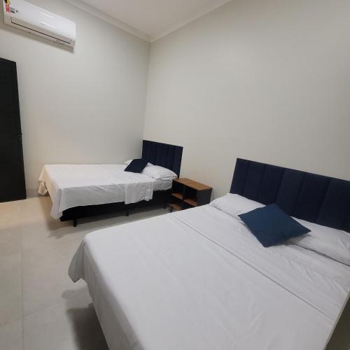 two beds in a room with white walls at Happy Buritis, eventos e hospedagem in Primavera do Leste