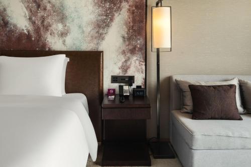 a bedroom with a bed and a couch and a lamp at Crowne Plaza Chengdu Wenjiang by IHG in Chengdu