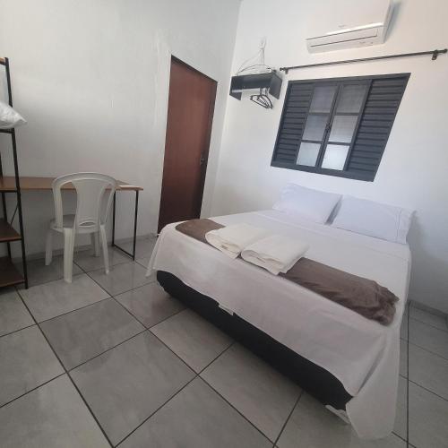 a bedroom with a bed and a table and a window at Casa Limoeiro in Primavera do Leste