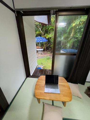 a laptop on a table in a room with a window at 与論ゲストハウス ズッ友荘 in Furusato