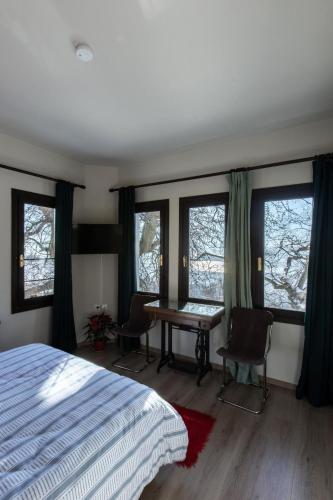 a bedroom with a bed and a table and windows at Stagiates Guest House at Pelion in Portaria