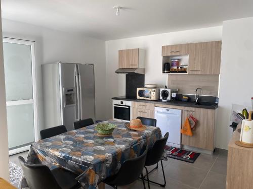 une cuisine avec une table avec des chaises et un réfrigérateur dans l'établissement Duplex T4 Climatisé avec Terrasse, Parking et Plage à Proximité - Port Leucate, 8 Pers. - FR-1-798-1, à Leucate