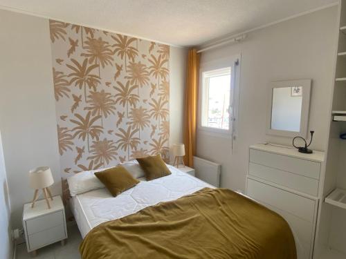 - une chambre avec un lit et un mur recouvert de papier peint dans l'établissement Port Leucate: T2 Alcove Climatisé, 6 Pers, Parking, Animaux bienvenus - FR-1-798-11, à Leucate