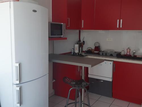 une cuisine avec des armoires rouges et un réfrigérateur blanc dans l'établissement Charmant T2 à Port Leucate - Proche Mer, Animaux Acceptés, Climatisation - FR-1-798-12, à Leucate