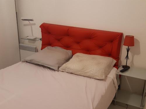 - un lit avec une tête de lit rouge et 2 oreillers dans l'établissement Charmant T2 à Port Leucate - Proche Mer, Animaux Acceptés, Climatisation - FR-1-798-12, à Leucate