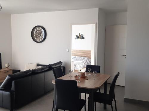 une salle à manger avec une table, des chaises et une horloge dans l'établissement Superbe T2 climatisé avec parking, 4 pers, proche plage - FR-1-798-23, à Leucate