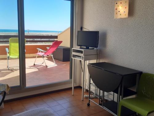 Cette chambre dispose d'une télévision et d'un balcon avec des chaises. dans l'établissement Studio Cabine 4 Pers. Face Mer avec Parking - Port Leucate - FR-1-798-32, à Leucate