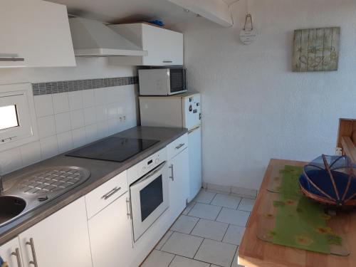 - une cuisine avec des appareils électroménagers blancs et une table dans l'établissement Port Leucate: Villa 6 pers. face à la mer, cosy, proche activités - FR-1-798-40, à Leucate