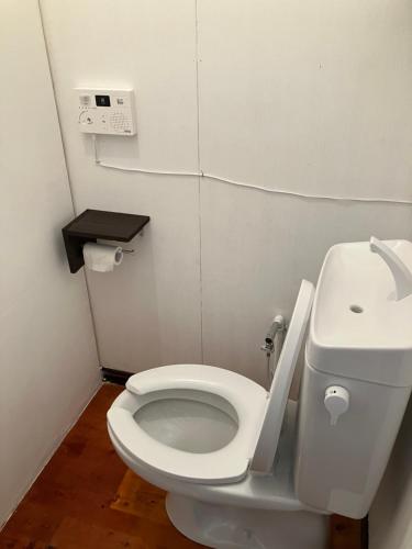 a bathroom with a white toilet and a sink at 与論ゲストハウス ズッ友荘 in Furusato