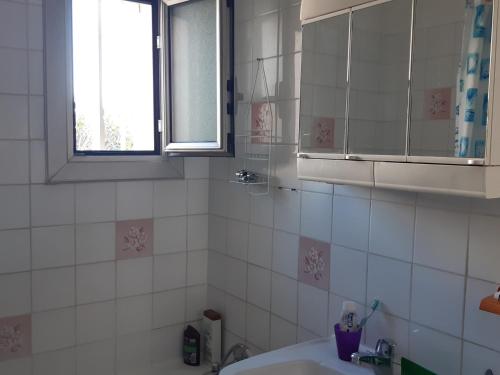 La salle de bains est pourvue de carrelage blanc, d'un lavabo et d'une fenêtre. dans l'établissement T2 Front de Mer, Rez-de-Chaussée, Port Leucate, Parking, 5 Personnes - FR-1-798-6, à Leucate