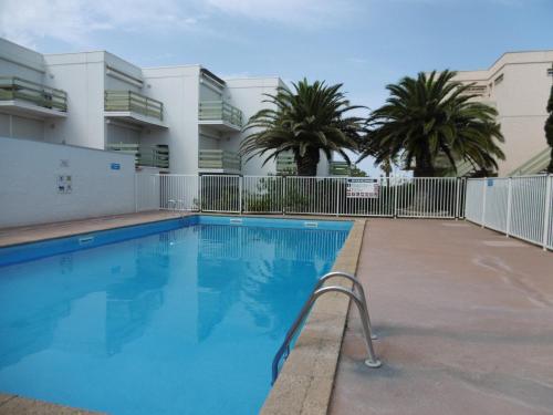 - une piscine bordée de palmiers et de bâtiments dans l'établissement Studio Cabine à Port Leucate : 4 Pers, Piscine, Front de Mer, Terrasse, Parking - FR-1-798-9, à Leucate
