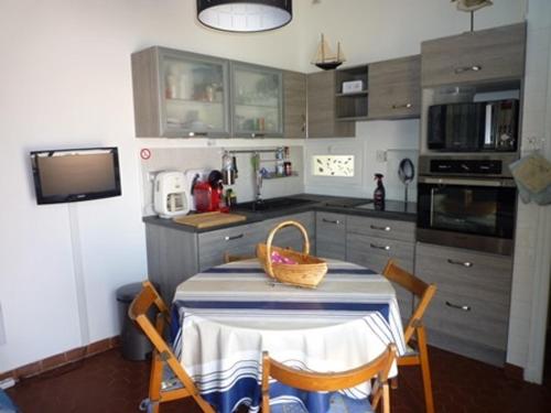 une cuisine avec une table et un panier dans l'établissement Charmant T2 climatisé à Port Leucate - Terrasse, Parking, Proche Mer, Animaux Bienvenus - FR-1-798-24, à Leucate