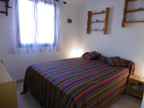 - une chambre avec un lit et une couverture rayée colorée dans l'établissement T2 Mezzanine Rénové à Port Leucate - Plage/Port à Pied, Parking Privé, Animaux Bienvenus - FR-1-798-26, à Leucate