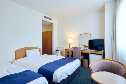 a hotel room with two beds and a desk and a television at Hotel Kumamoto Terrsa in Kumamoto