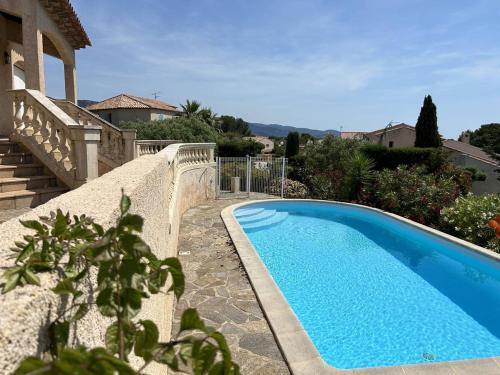 - une piscine bleue à côté d'une maison dans l'établissement Villa calme avec piscine privée, parking, 3 chambres, pour 6 à Bormes-les-Mimosas - FR-1-251-837, à Bormes-les-Mimosas
