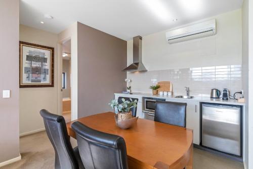 a kitchen with a wooden table and chairs at Moonah Links Apartments - Fairway Views, Golf, Hot Springs in Fingal