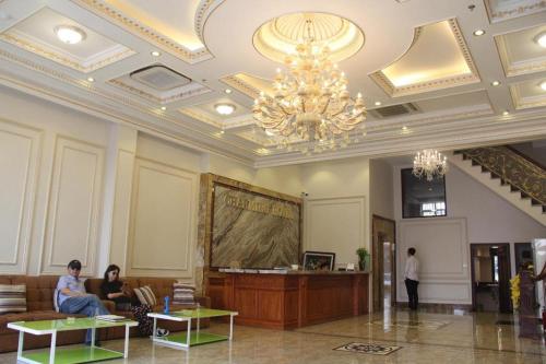 a lobby with a chandelier and people sitting in a room at Bacninh Charming Hotel in Bắc Ninh