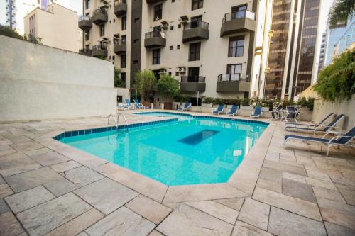 a swimming pool with chairs and a building at Apartamento Duplex Place Vendome! Moema, 58m2, Amplo, Conforto, Luxo! Servicos, Estacionamento, Internet, Metro! in Sao Paulo