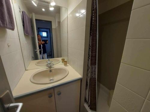 un homme prenant une photo d'une salle de bains avec lavabo dans l'établissement Studio Cabine Lumineux avec Piscine, Parking et Loggia au Grau d'Agde - FR-1-423-310, au Grau-dʼAgde