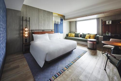 a bedroom with a large white bed and a living room at voco Osaka Central by IHG in Osaka