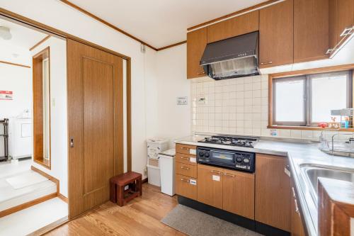 a kitchen with wooden cabinets and a stove top oven at Popotel 2 NIKAI in Matsumoto