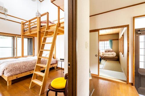 a bedroom with bunk beds and a living room with a ladder at Popotel 2 NIKAI in Matsumoto