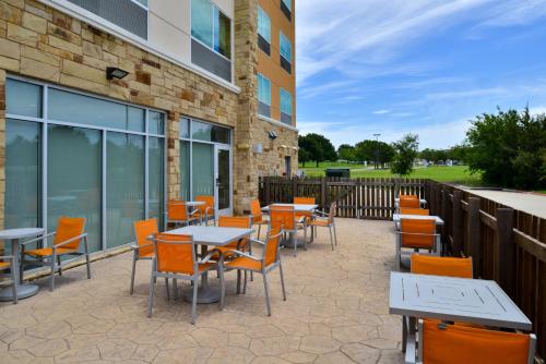 a patio with tables and chairs next to a building at Holiday Inn Express & Suites - Wylie West by IHG in Wylie
