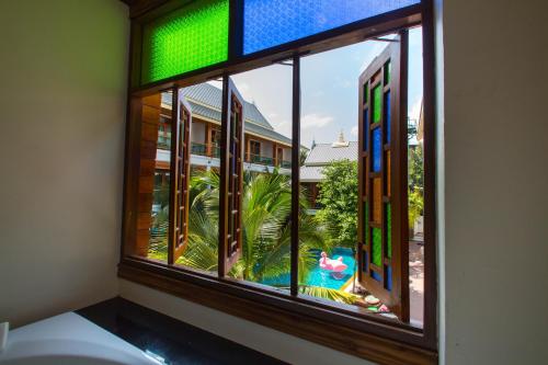 a window with a view of a palm tree outside at Pingviman Hotel in Chiang Mai