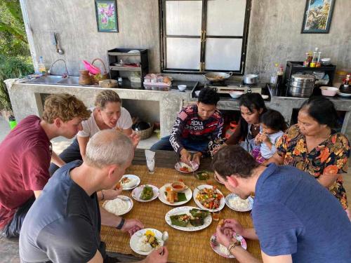 a group of people sitting around a table eating food at Battambang Eco Stay &cooking class in Battambang