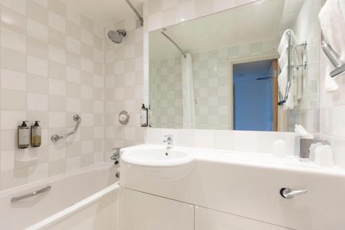 a white bathroom with a sink and a tub at Holiday Inn Basildon, an IHG Hotel in Basildon
