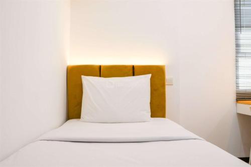 Una cama con una almohada blanca encima. en Spacious 3BR with Good View at Gateway Pasteur Apartment By Travelio, en Bandung
