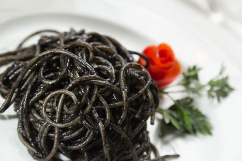 a pile of noodles on a plate with a red rose at Hotel Milton Rimini in Rimini