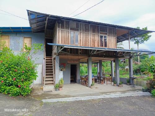 a wooden house with a porch and a table at Talaga Tomohon Home Stay and Fishing Pond in Tomohon