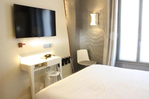une chambre avec un lit et une télévision sur un mur dans l'établissement Le Malown, à Paris