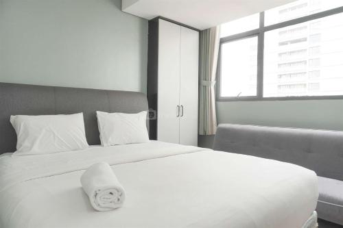 a bedroom with a white bed with a towel on it at Restful and Modern 3BR at Daan Mogot City Apartment By Travelio in Jakarta