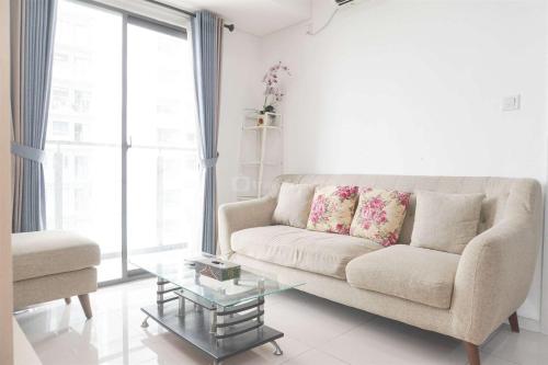a living room with a couch and a glass table at Restful and Modern 3BR at Daan Mogot City Apartment By Travelio in Jakarta