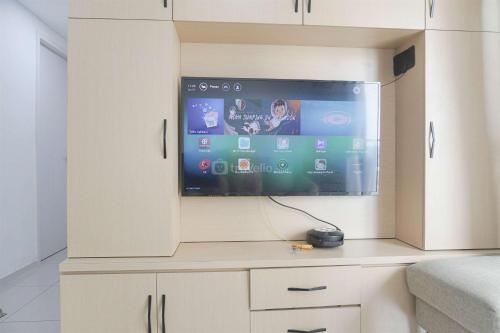 a flat screen tv sitting on top of a cabinet at Restful and Modern 3BR at Daan Mogot City Apartment By Travelio in Jakarta