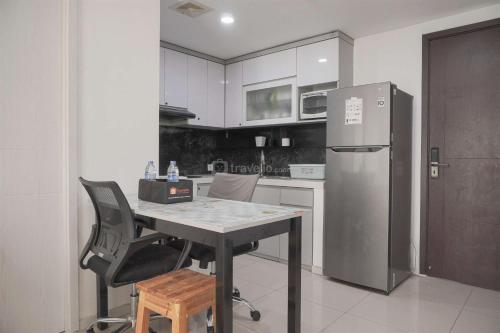 a kitchen with a table and a refrigerator at Restful and Modern 3BR at Daan Mogot City Apartment By Travelio in Jakarta