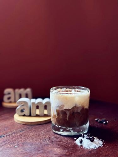 a glass of coffee sitting on a table next to shoes at Âm Ấm Đà Lạt Boutique Hotel & Cozy Bistro in Khu Chi Lăng