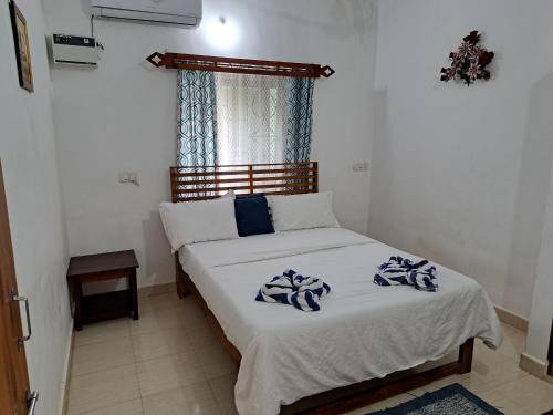 a bedroom with a bed with blue and white sheets at Brittos Homestay in Mandrem