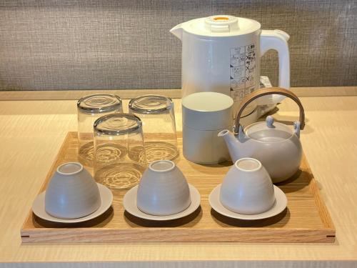 a wooden tray with dishes and a tea pot on it at Ryokan Miyoshi in Nagoya