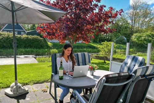 a woman sitting at a table with a laptop at Ferienhaus Lillian mit großer Terrasse in Anjum