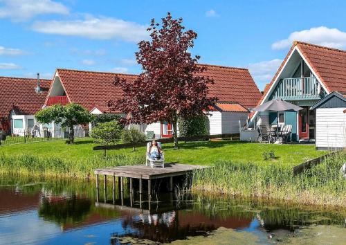 a woman sitting on a dock next to a lake at Ferienhaus Lillian mit großer Terrasse in Anjum