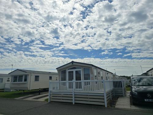 a small house with a porch in a parking lot at Modern caravan Robin Hood Rhyl in Rhyl