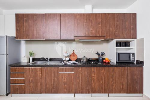 a kitchen with wooden cabinets and a sink and a microwave at Sattva by Kozystay - Kuningan in Jakarta