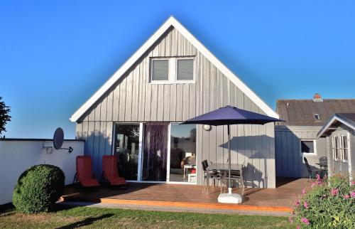 une maison avec un parasol sur une terrasse en bois dans l'établissement Ferienhaus mit Grill und Garten in Neukirchen, à Neukirchen