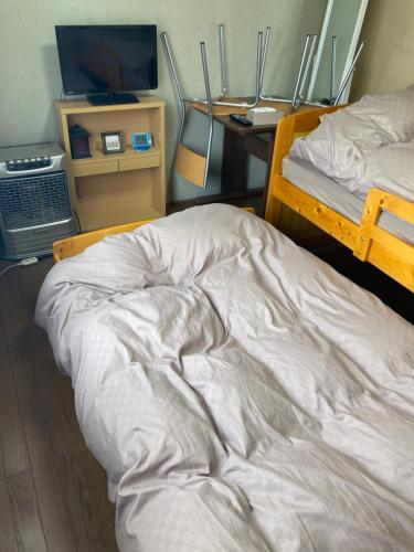 an unmade bed in a room with a television at Home Yasuda in Otaru