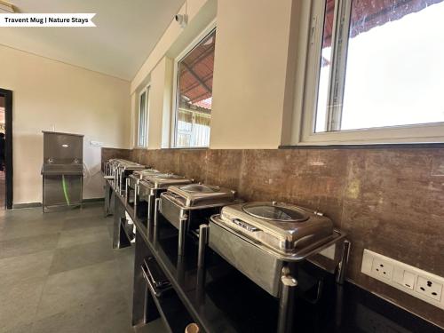 a row of stainless steel sinks in a room at Pepper Corn Retreat By Travent Mug in Sakleshpur