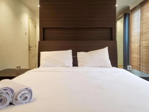 a bedroom with a large bed with white sheets and pillows at Minimalist and Comfy 1BR at The Boulevard Apartment By Travelio in Jakarta
